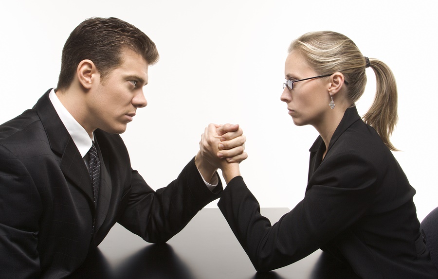 Side view of Caucasian mid-adult businessman and businesswoman arm wrestling on table.